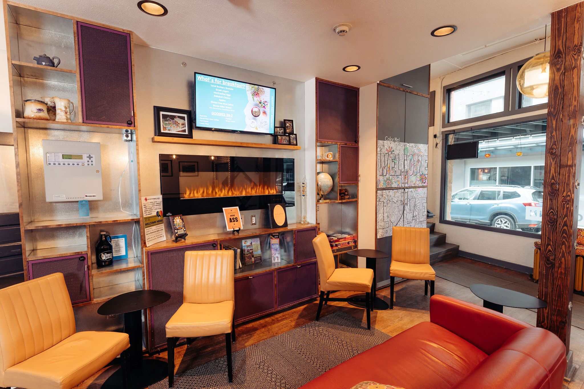 A cozy lounge area with leather seating, a fireplace, and a television displaying a menu.
