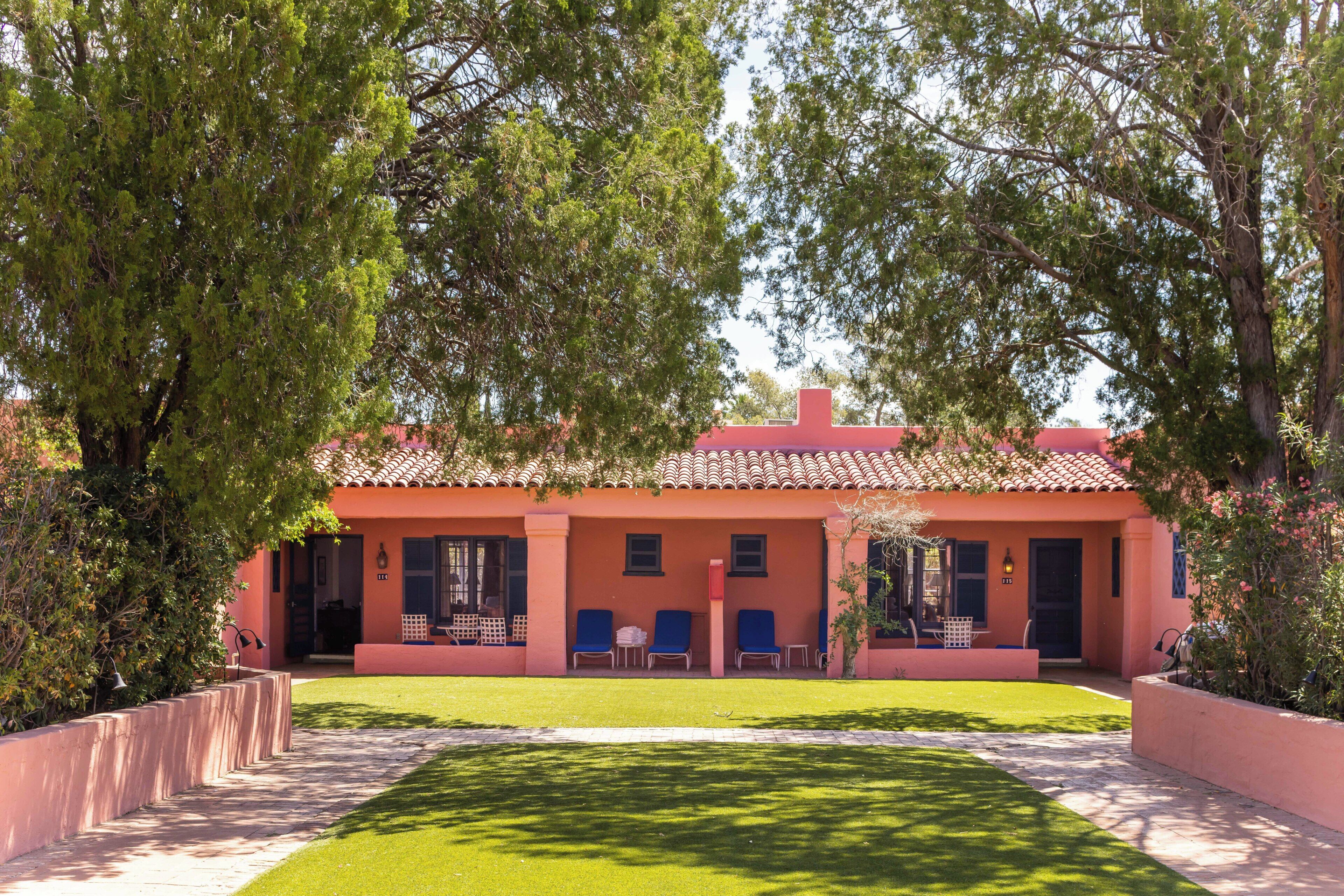A building with a red facade, a tiled roof, and a well-maintained lawn.