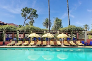 Una piscina al aire libre, sombrillas, sillones reclinables de piscina