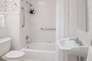 Un bany amb un vàter blanc, una banyera, un lavabo i una dutxa amb cortina.