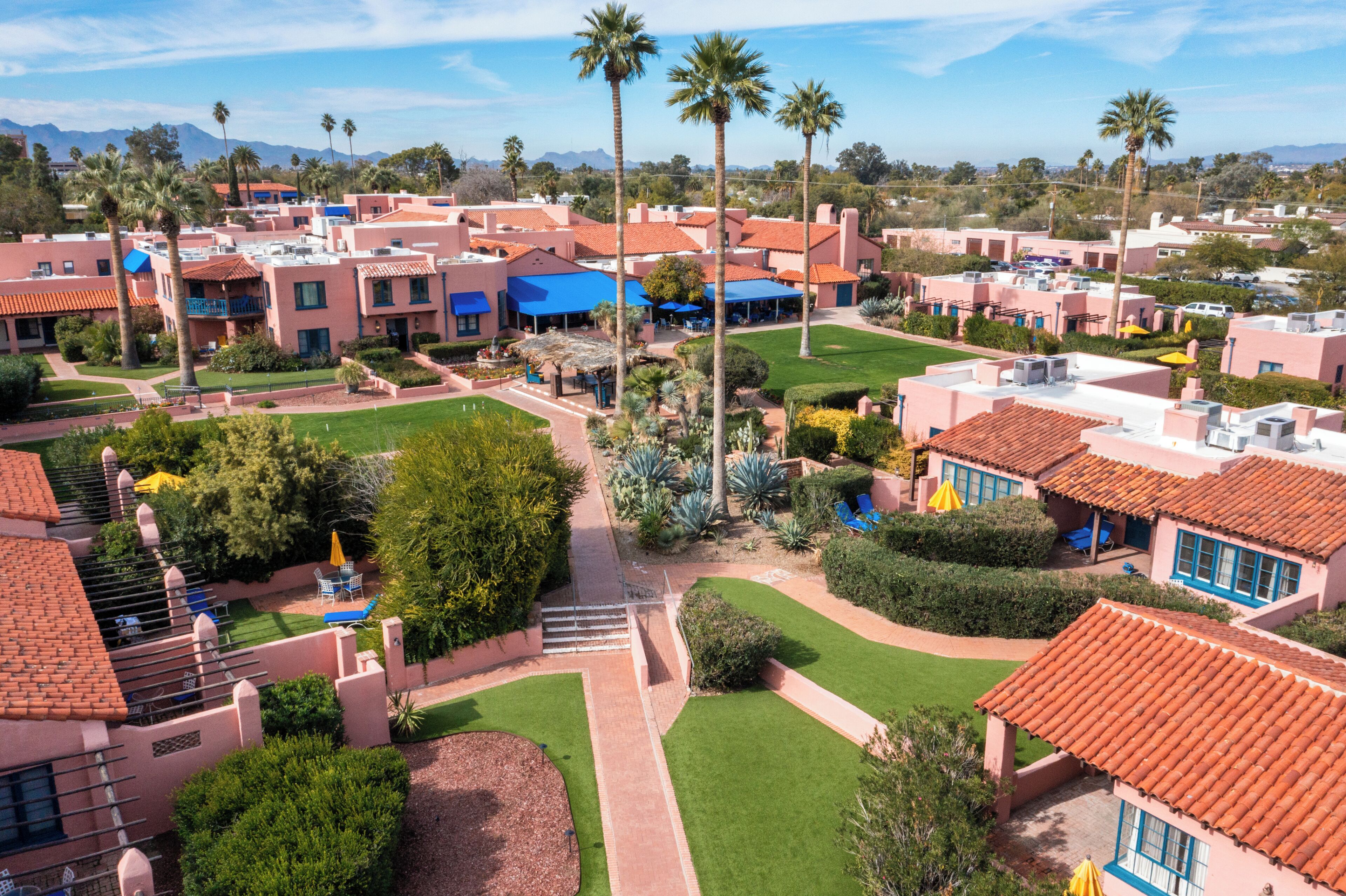 A resort with multiple buildings, palm trees, and a well-maintained lawn.
