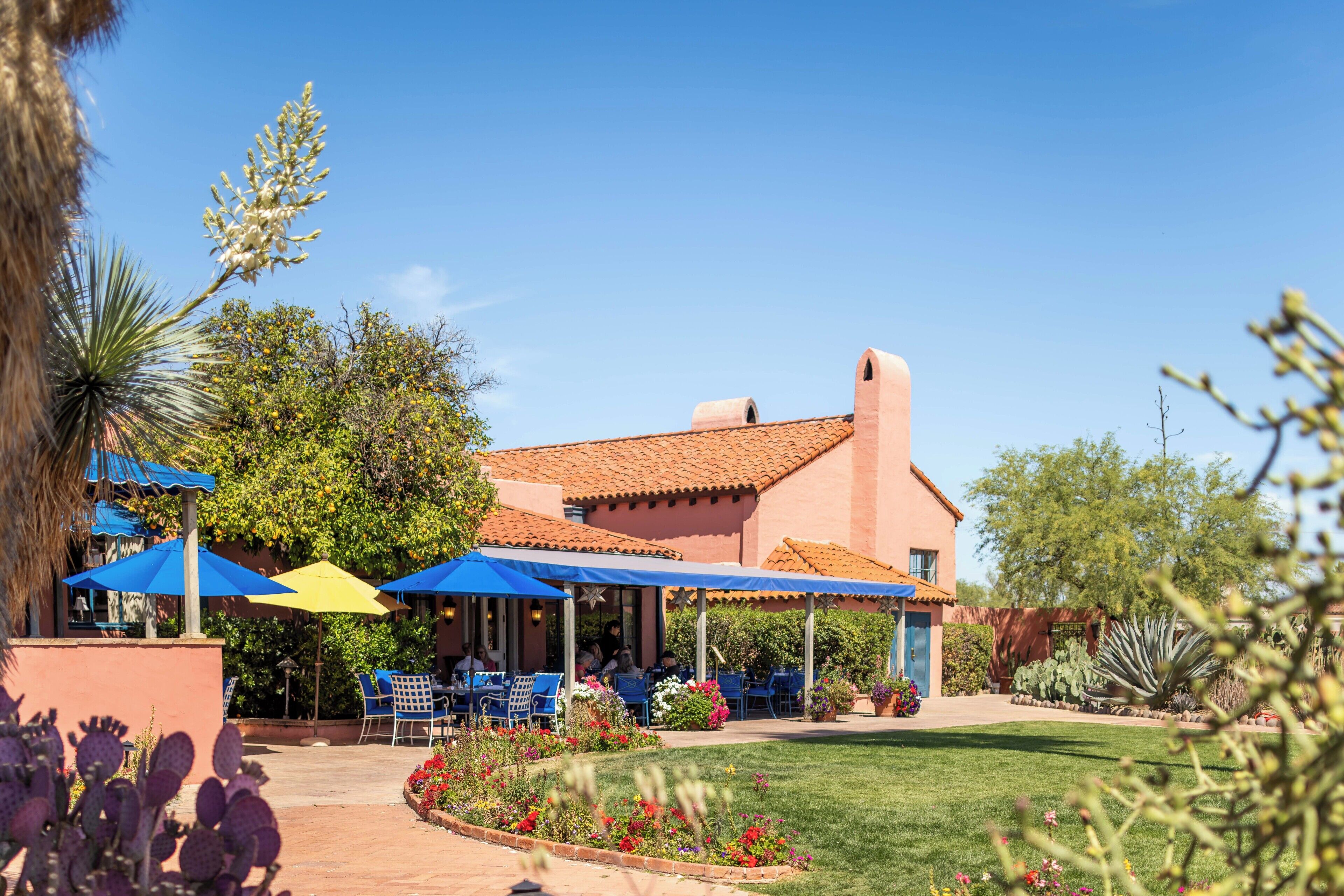 A building with a red-tiled roof and a patio area with blue umbrellas.