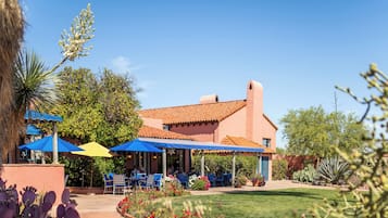 A building with a red-tiled roof and a patio area with blue umbrellas.