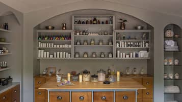 A kitchen with wooden cabinets, a central island, and shelves above containing various kitchen items and spices.