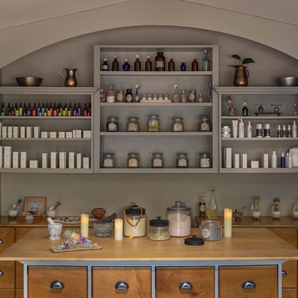A kitchen with wooden cabinets, a central island, and shelves above containing various kitchen items and spices.