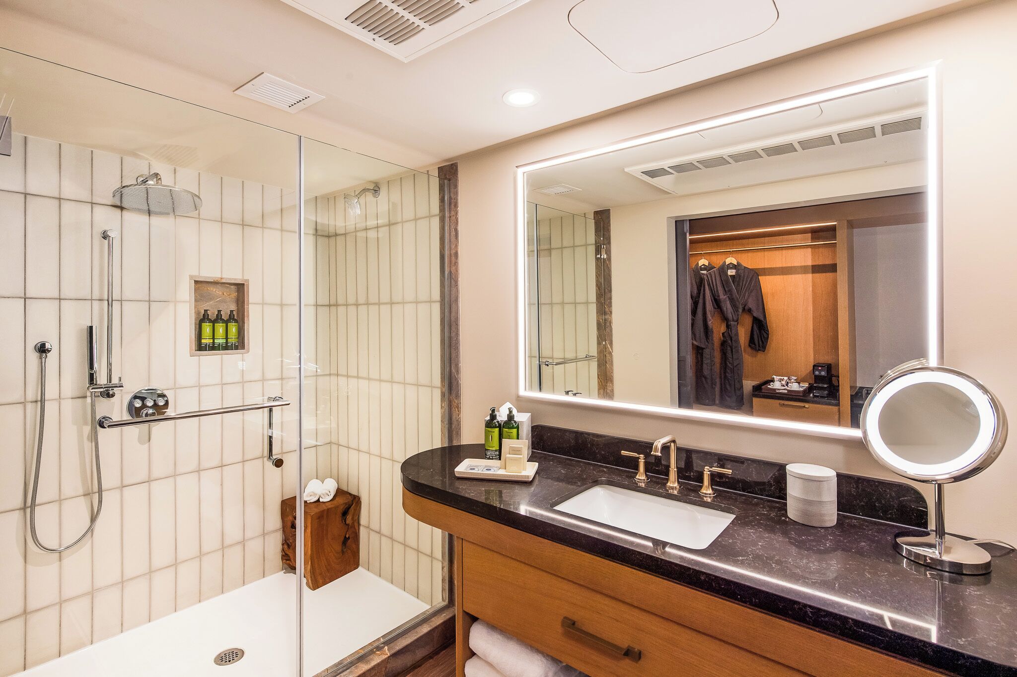A modern bathroom with a glass-enclosed shower, a vanity with a sink and mirror, and a wooden cabinet.