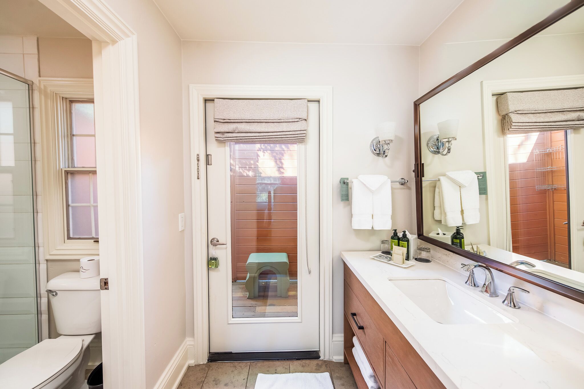 A bathroom with a toilet, sink, and mirror.