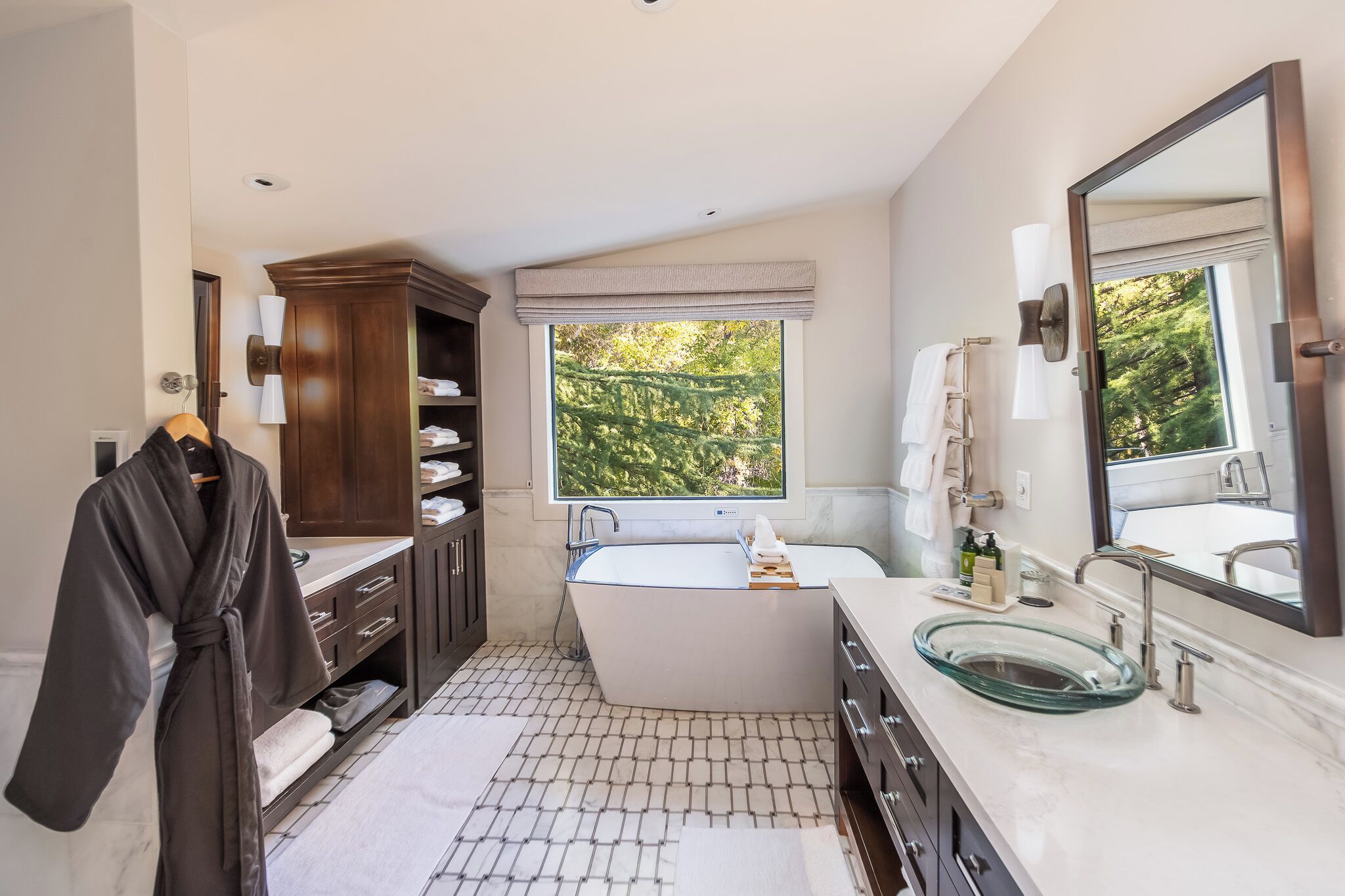 A modern bathroom with a bathtub, a glass sink, and a large mirror.