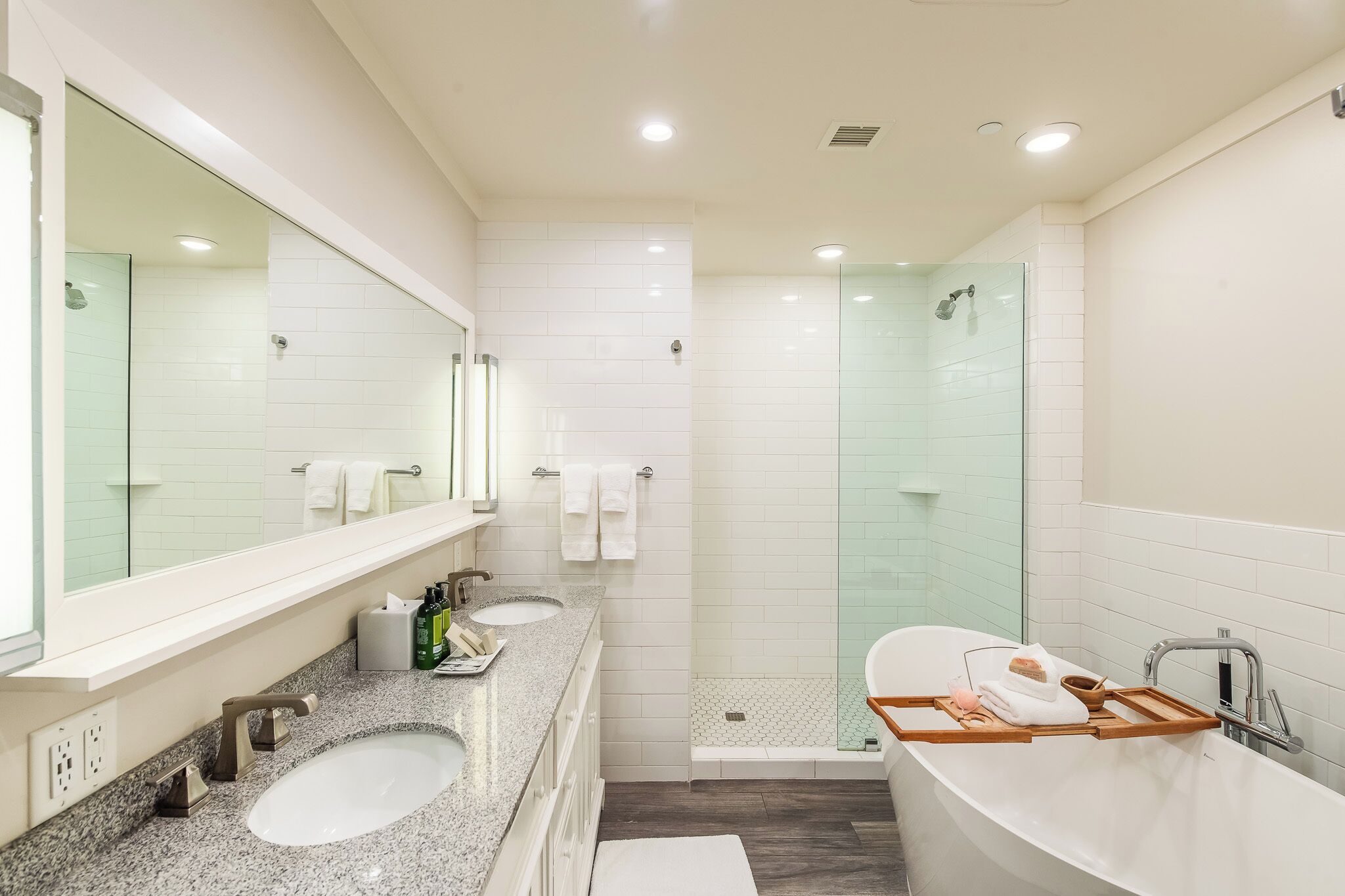 Un baño moderno con un espejo grande, dos lavamanos, una ducha y una bañera.