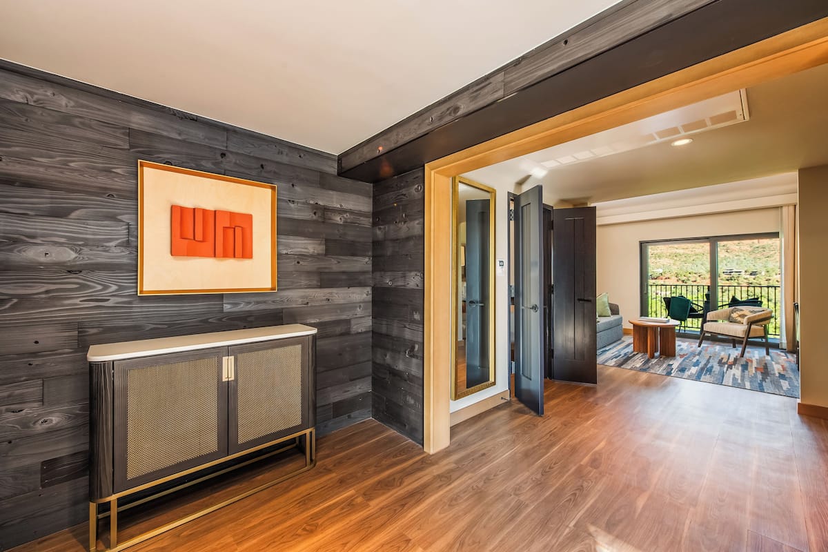 Un interior moderno con un panel de madera oscura, un radiador y vistas a un balcón con mobiliario exterior.