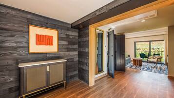 A modern interior with a dark wood panel wall, a radiator, and a view to a balcony with outdoor furniture.