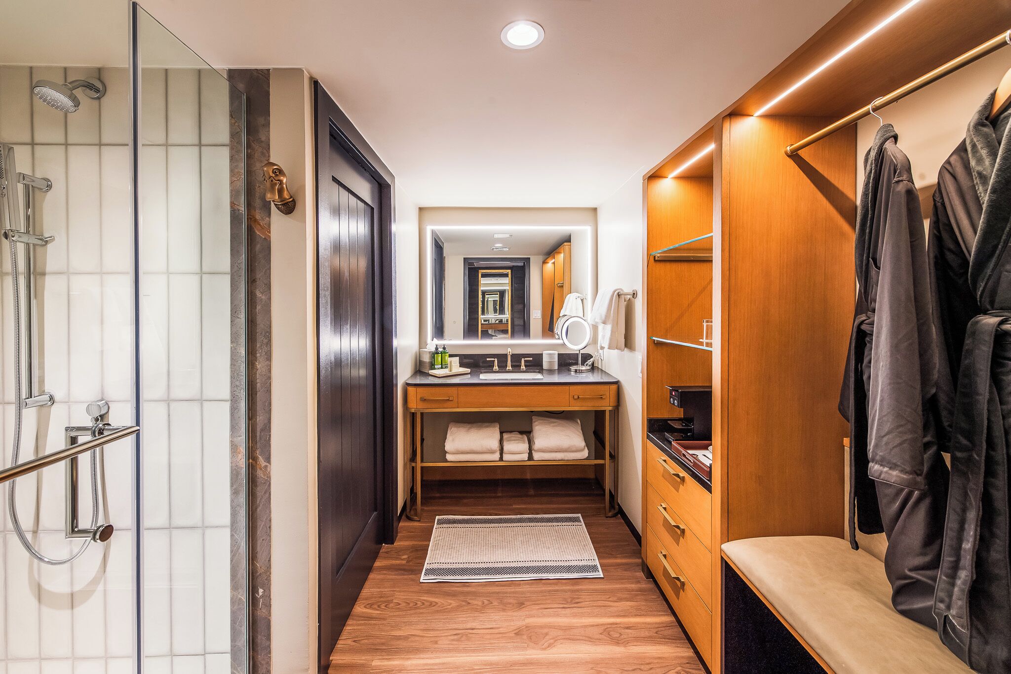 A compact bathroom with a shower, vanity, and storage.