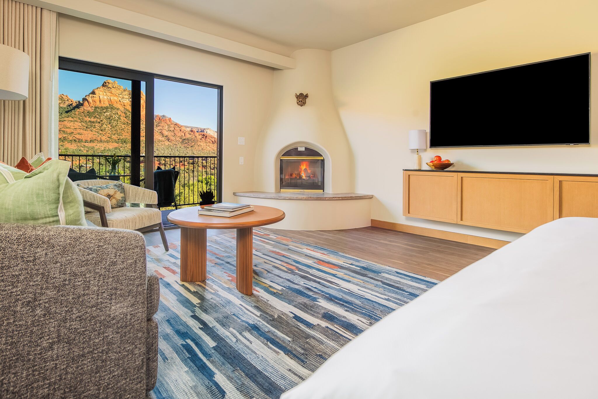 A hotel room with a large window, a fireplace, a television, and a bed.