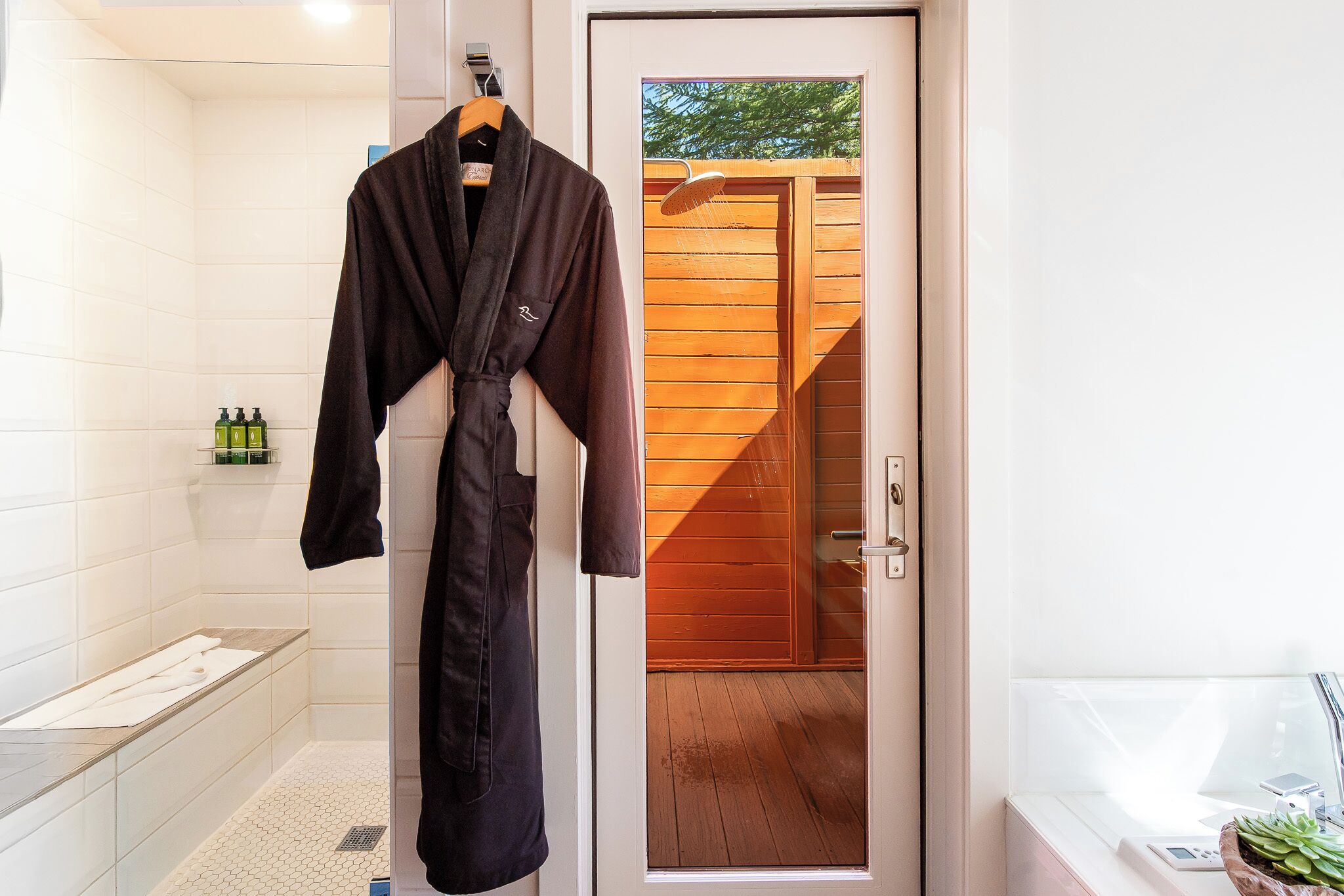 A bathroom with a bathtub, a shower, and a wooden door leading outside.