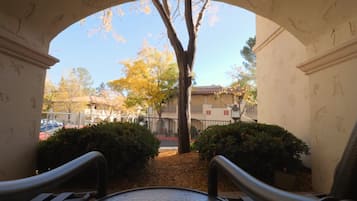 Relax in this serene outdoor seating area with a view of a tree and a nearby building.
