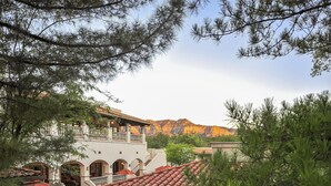 A hotel with a courtyard, arched walkways, and a mountain backdrop.