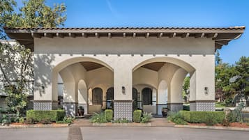 A building with a tiled roof, multiple arches, and a paved entrance area with plants.