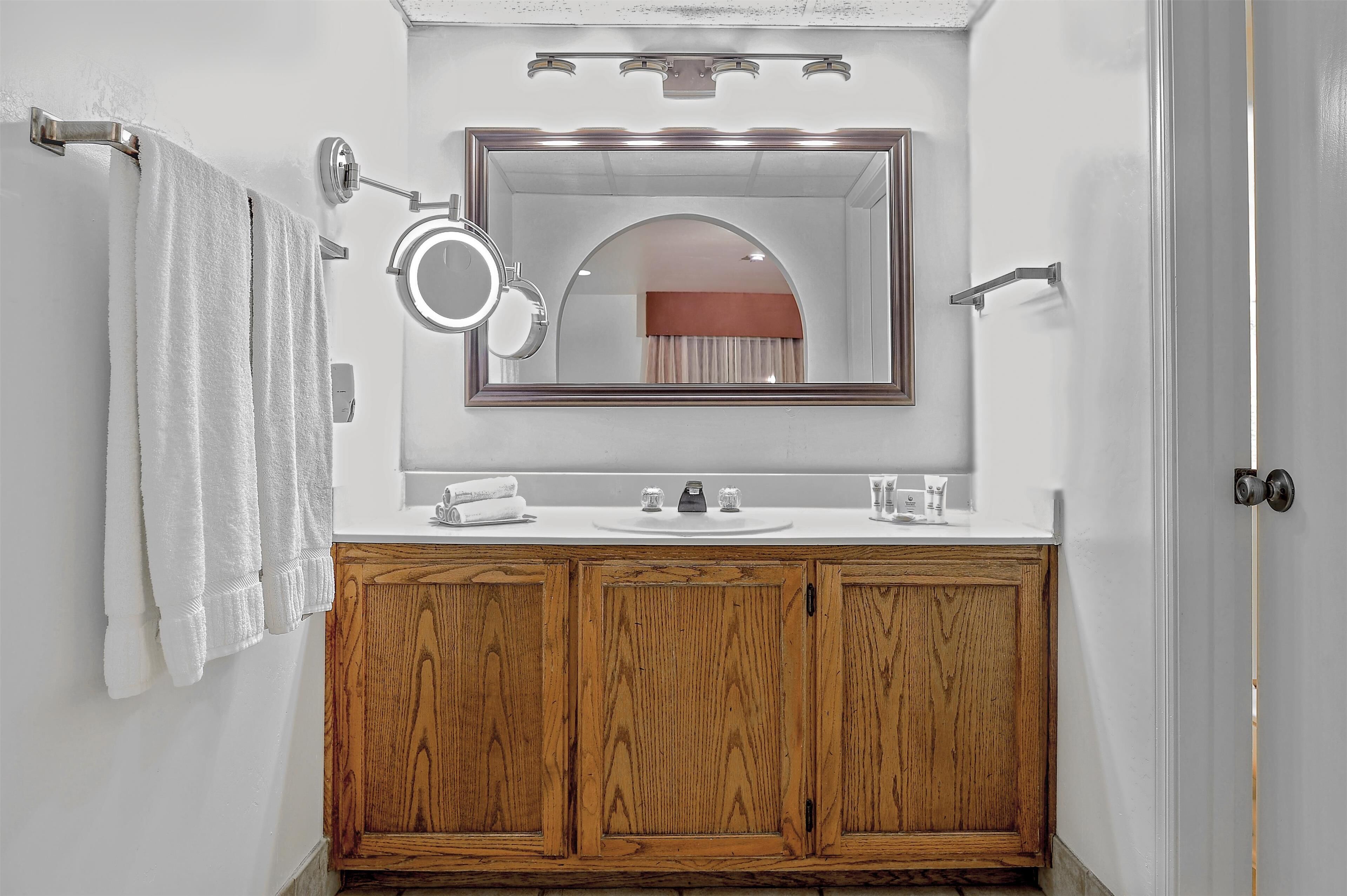Un baño con tocador de madera, un espejo y un perchero para toallas.