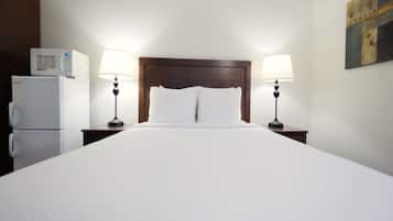 Habitación de hotel con una cama grande, dos lámparas de noche, un microondas y un refrigerador.