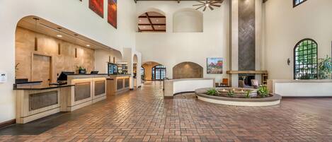 A spacious lobby with a brick floor, a reception desk, and a fireplace.