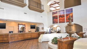 A spacious lobby with a reception desk, a large fountain, and artwork on the walls.