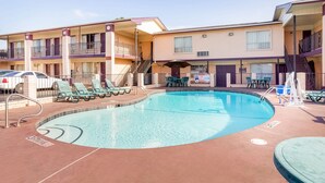 A pool area with lounge chairs and a staircase leading to a balcony.