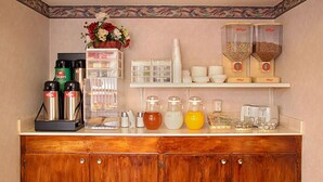 A kitchenette with a coffee maker, tea kettle, and various containers on the counter.