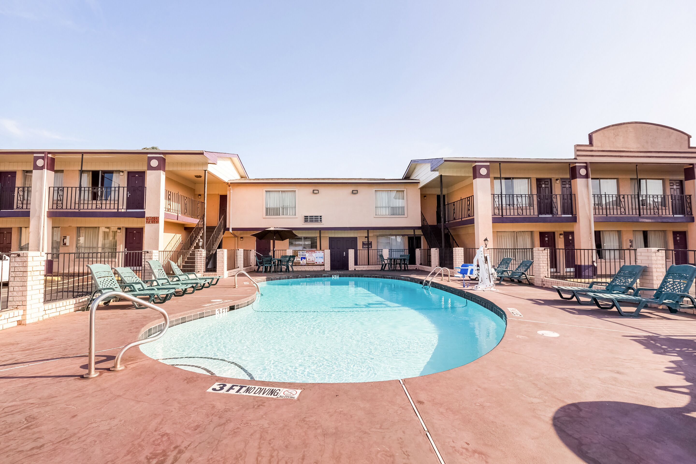 A hotel with a swimming pool, multiple balconies, and outdoor seating.