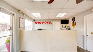 A hotel reception area with a marble reception desk, a clock, and a monitor on the wall.