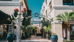 An Italian restaurant entrance with a sign, potted plants, and a clear sky. - Balboa Inn, On the Beach (Newport Beach)
