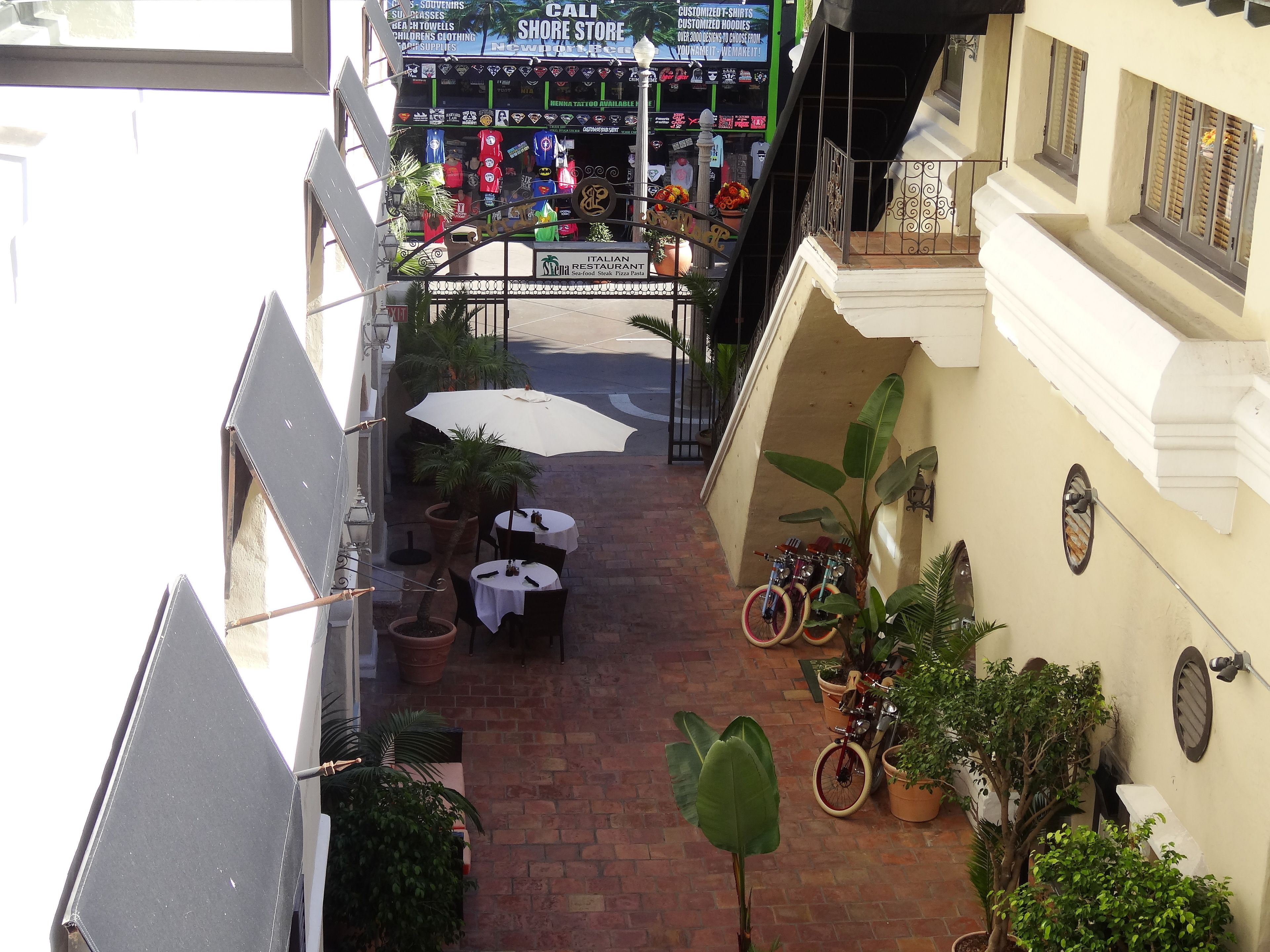 Un patio con mobiliario exterior, macetas con plantas y una tienda con diversos artículos a la venta.
