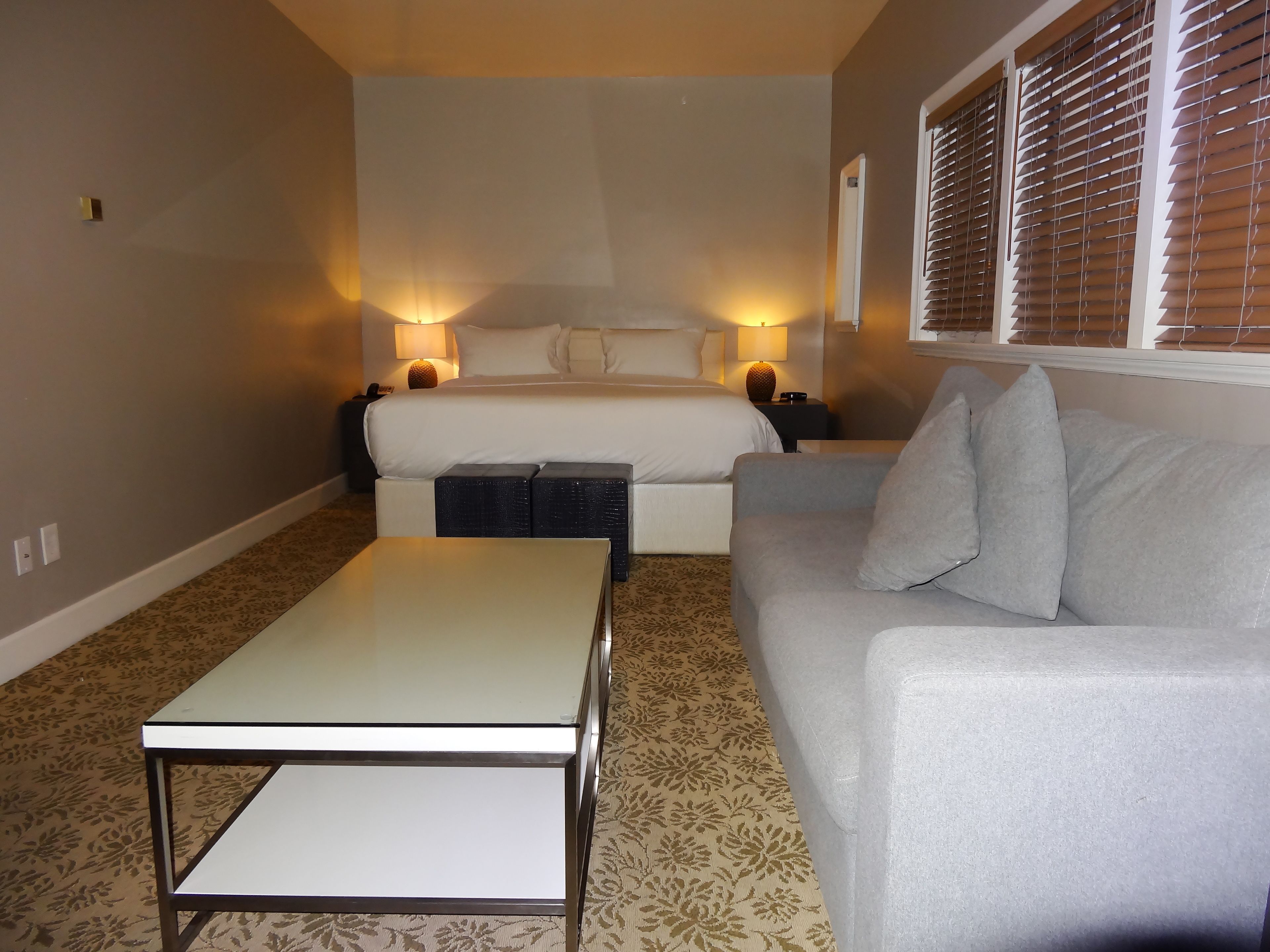 A hotel room with a bed, two bedside tables, a sofa, and a small table.