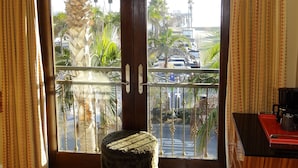 A room with a large window overlooking a street with palm trees and parked cars. - Balboa Inn, On the Beach (Newport Beach)