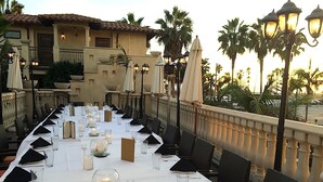 A long dining table set for a formal event with white tablecloths, candles, and glassware. - Balboa Inn, On the Beach (Newport Beach)