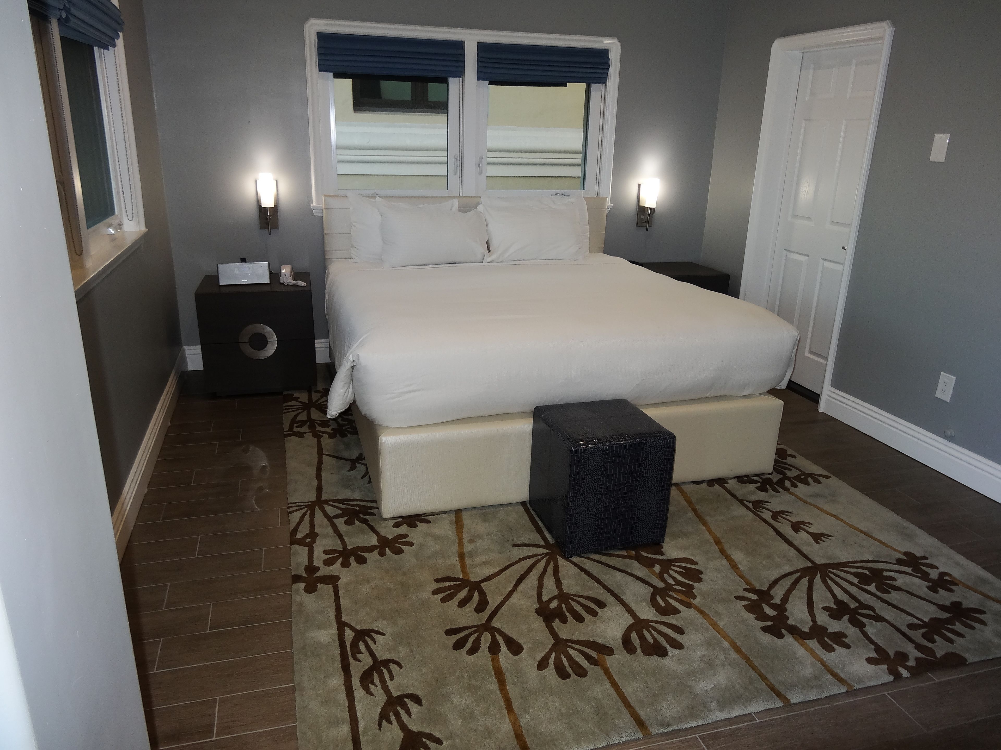 Un dormitorio ordenado con una cama grande, lámparas de noche, una mesita de noche y una alfombra decorativa.