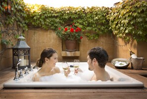 A couple in a hot tub with a potted plant and a candle in the background. - Bernardus Lodge & Spa (Carmel Valley)