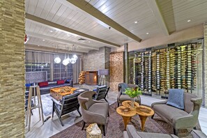 A modern lounge area with a fireplace, comfortable seating, and a wine display.