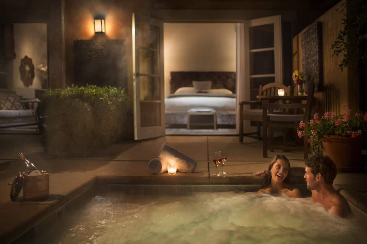 A couple relaxing in a hot tub with a view of a bedroom.