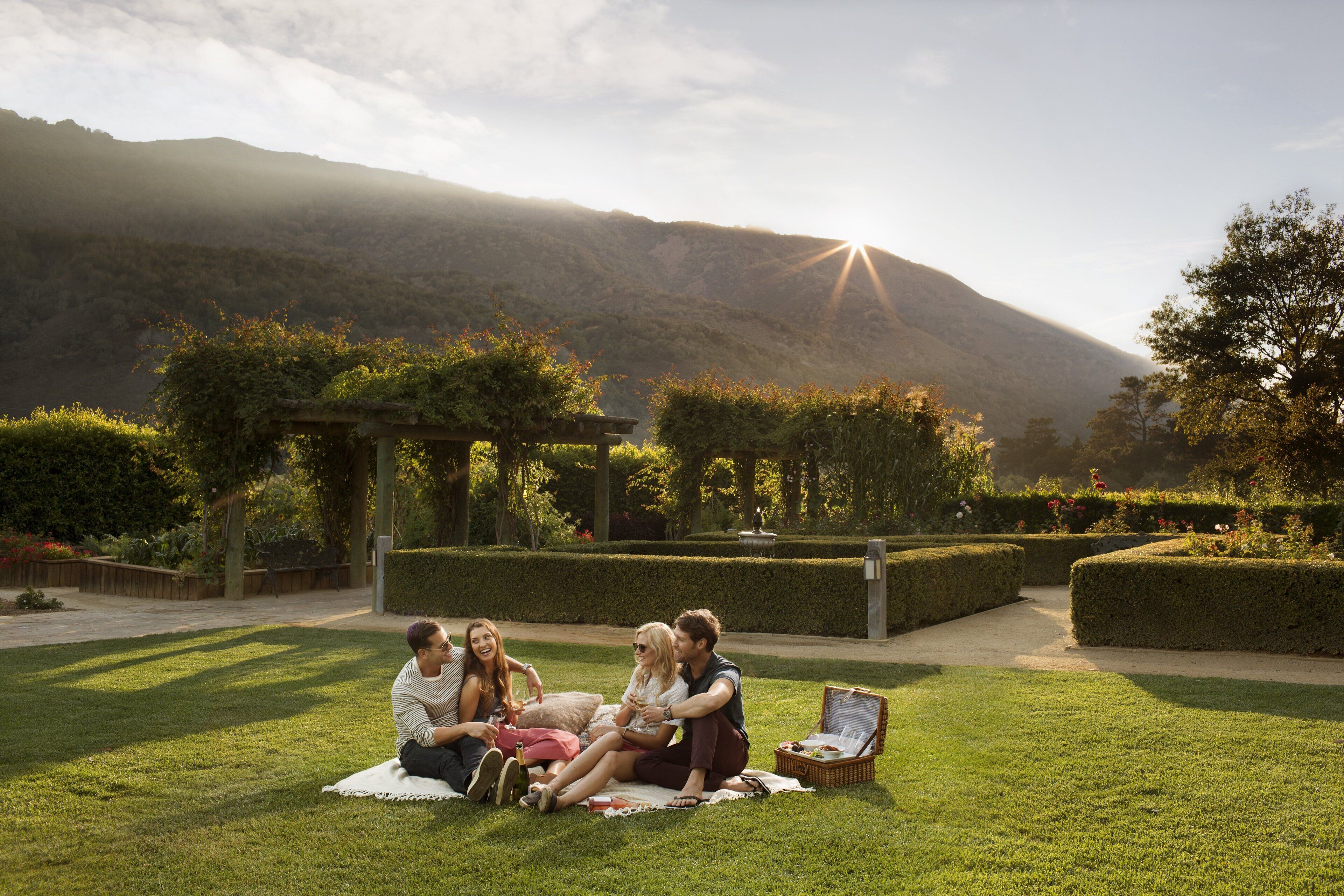 Un groupe de personnes est assis sur une couverture dans un parc, avec une montagne en arrière-plan.