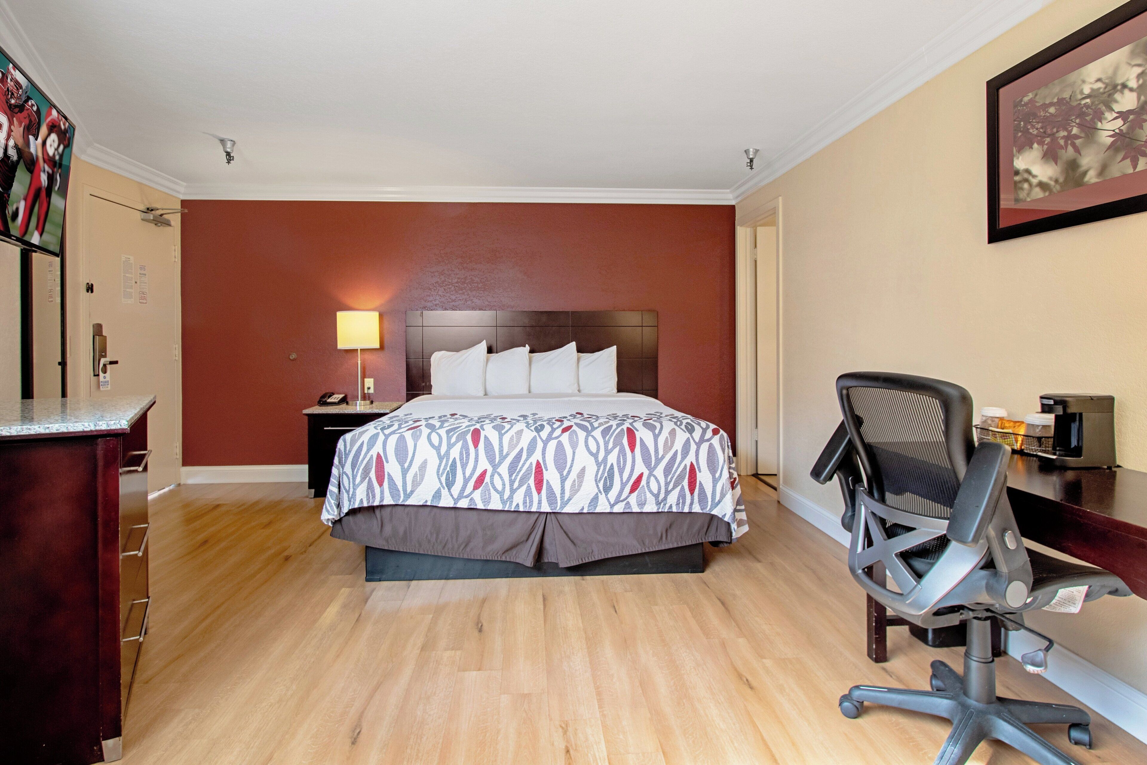 Une chambre d’hôtel avec un lit, un bureau, une chaise et un tableau au mur.