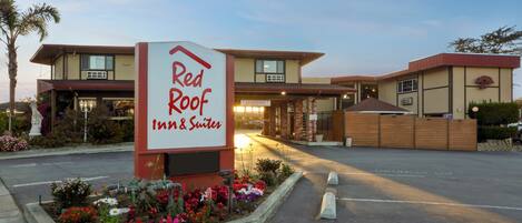 Ein Red Roof Inn & Suites mit einladbarem Eingang, einem angelegten Garten und einem Parkplatz.