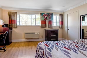 Ein Schlafzimmer mit Bett, Schreibtisch, Stuhl, Heizung und einem Fenster mit Vorhängen.