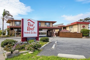 Ein Red Roof Inn & Suites mit freiem Zugang, einem Parkplatz und einer begrünten Fläche mit Blumen.