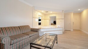 A modern living room with a sofa, a glass coffee table, and a large mirror reflecting a bathroom with a bathtub and a sink. - Red Roof Inn & Suites Monterey (Monterey)