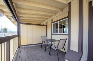 Un área de estar al aire libre techada con mesa y sillas, una ventana y vistas del exterior.