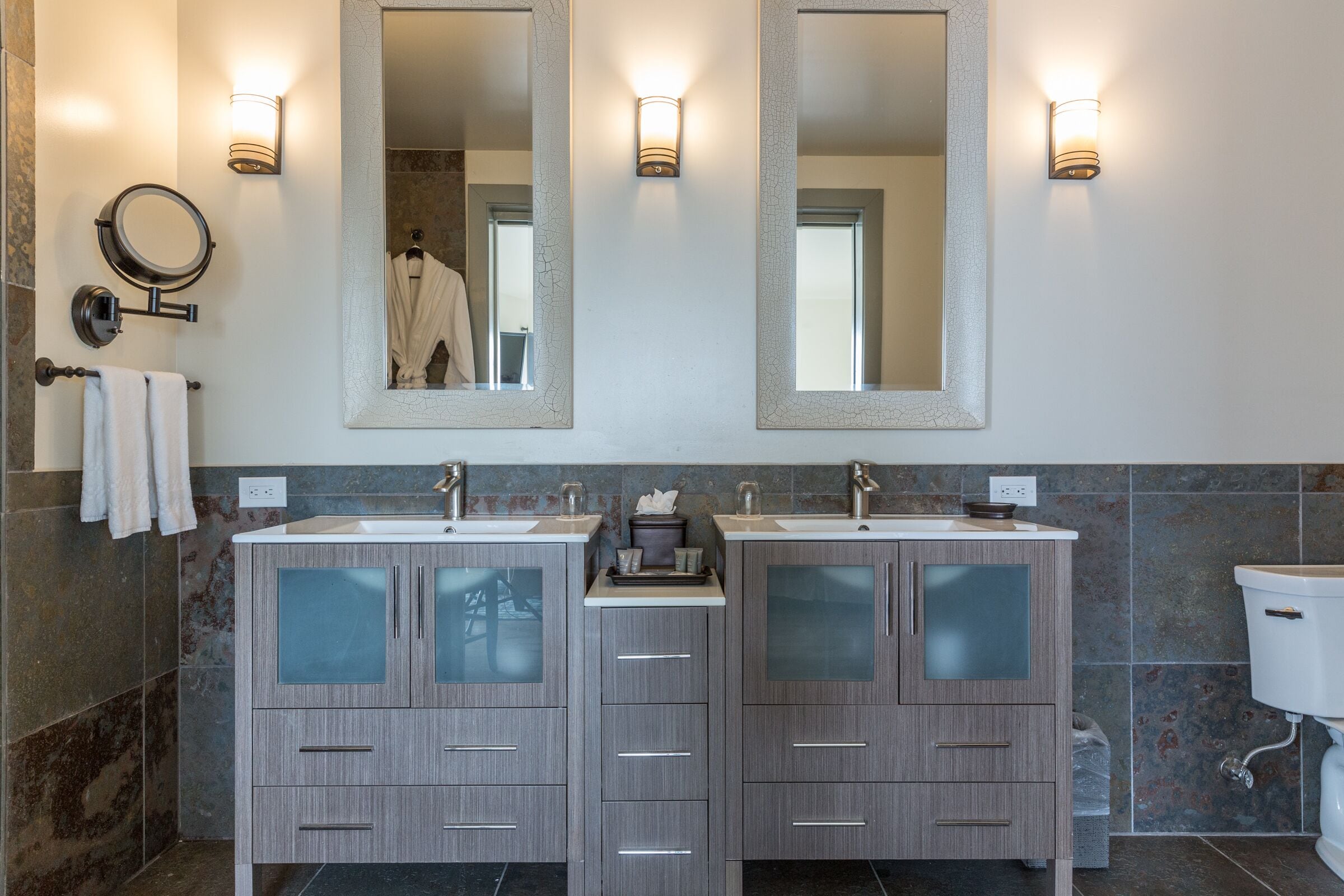 A modern bathroom with two sinks, a large mirror, and wall sconces.