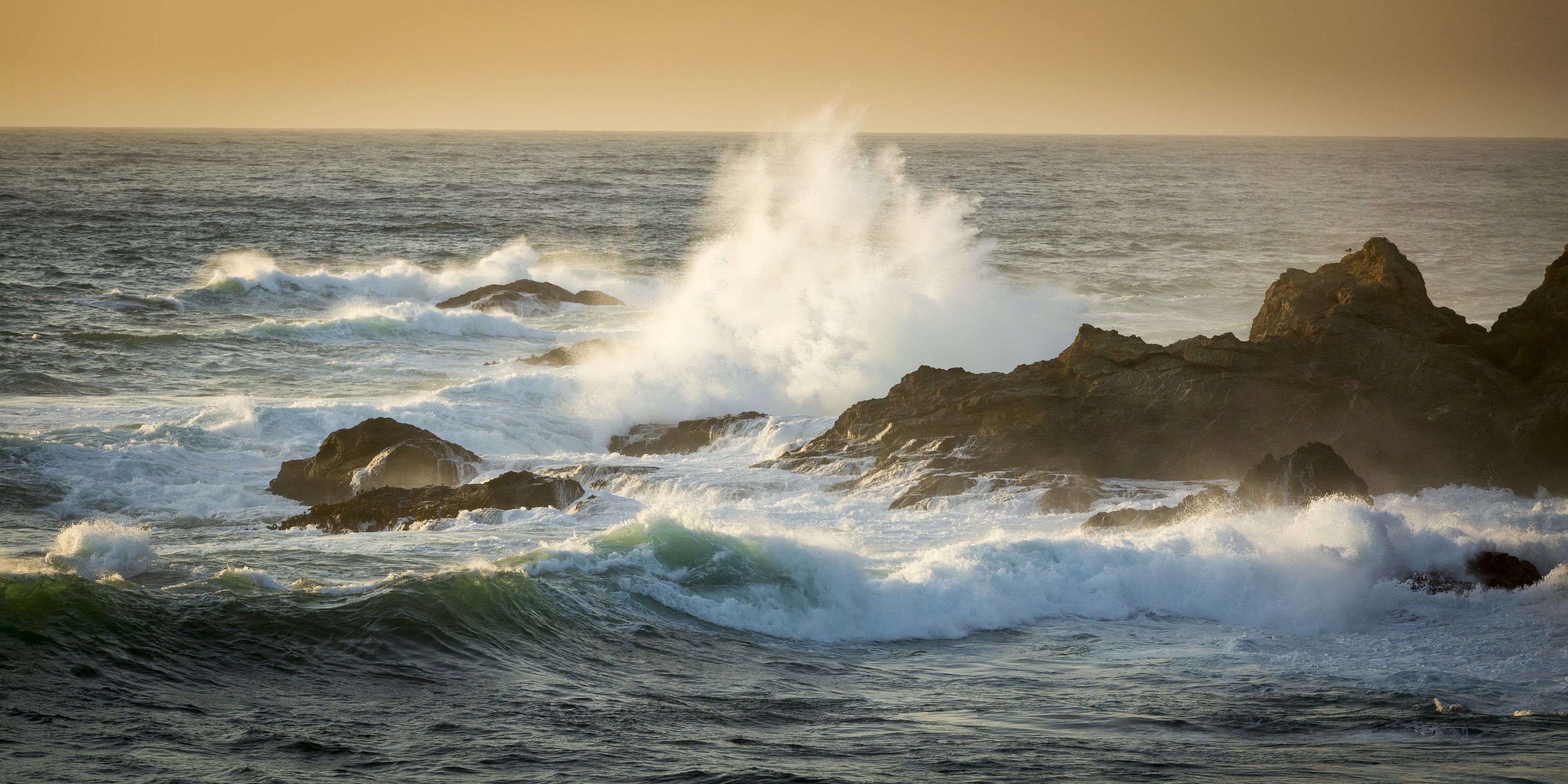 A coastal scene with waves crashing against rocky outcrops.