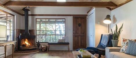 Una sala de estar acogedora con chimenea, vigas de madera, un banco, un sofá y una mesita de centro.