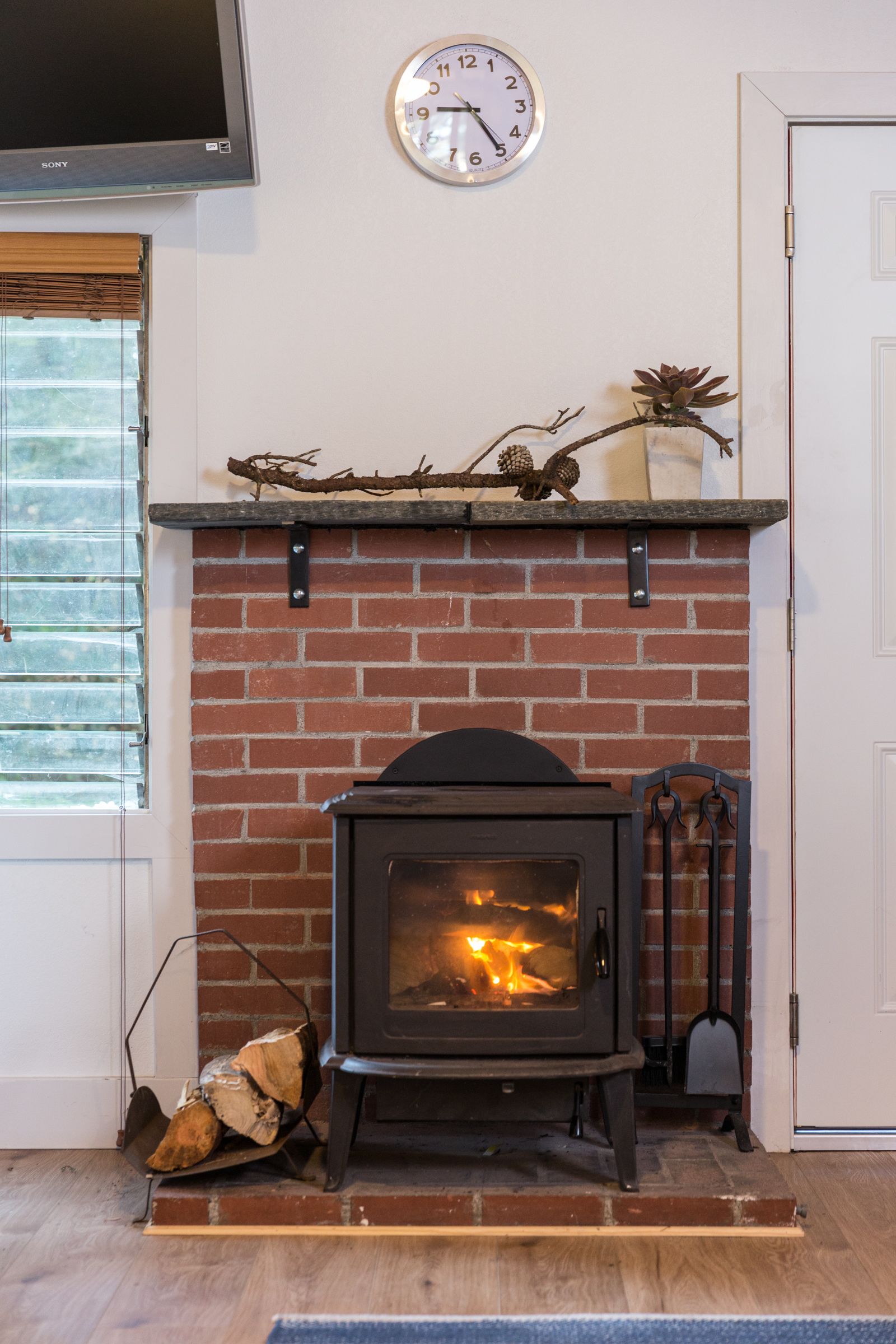A fireplace with a brick wall, a clock above it, and a door to the right.