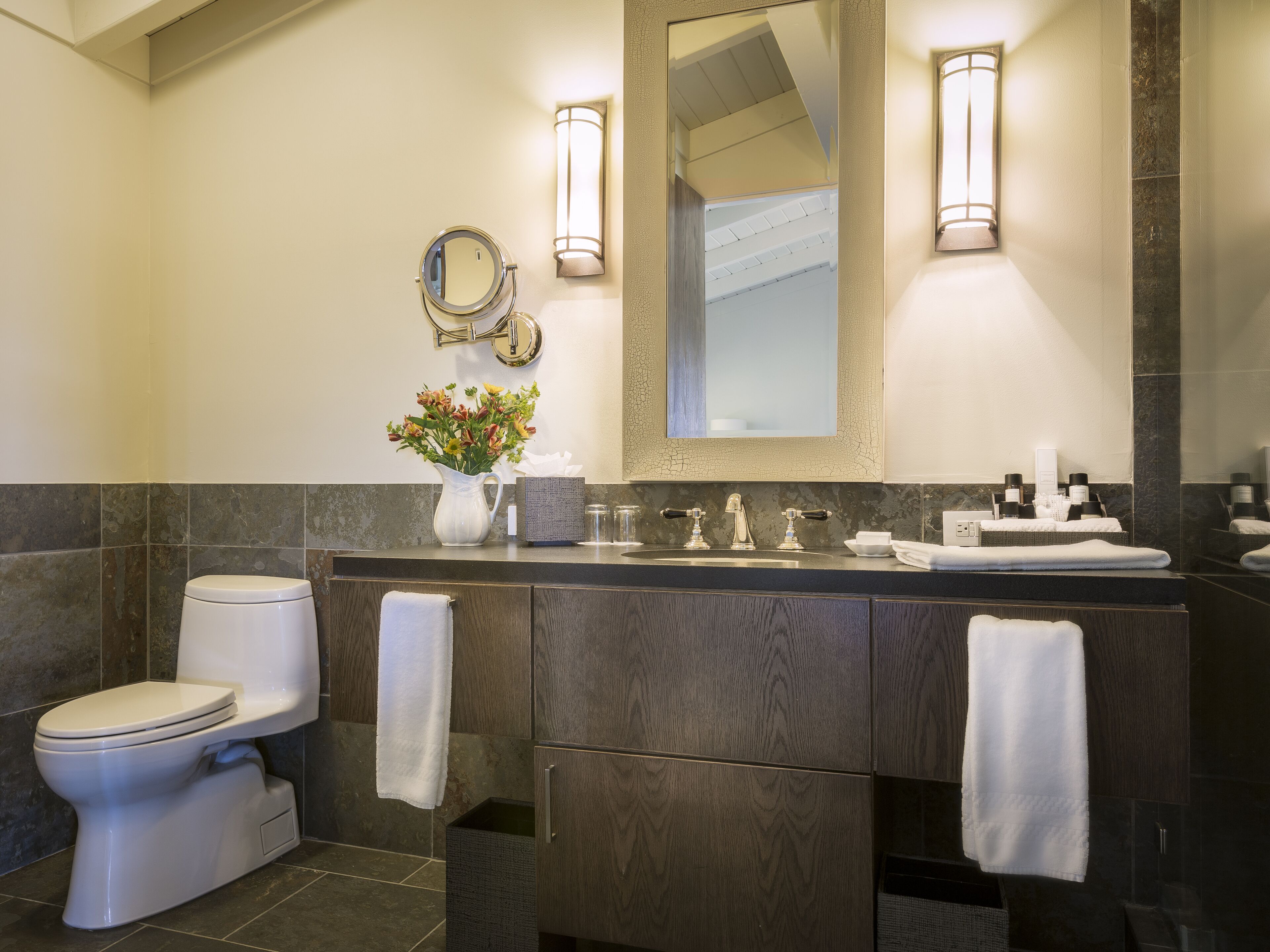 A modern bathroom with a toilet, vanity, and a large mirror.